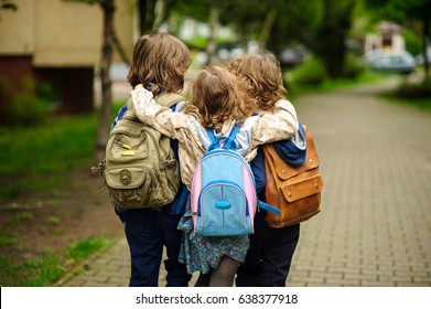 Three little school students go in an embrace to school. Children's friendship. - Shutterstock ID 638377918
