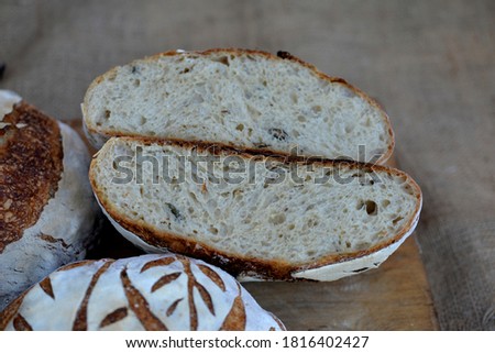 Three loafs of home baked wheat bread;  crusty banana bread on wooden board with bred texture of loaf cut in half