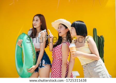 Three lovely young girl bestfriends wearing summer outfit over orange background. Summer vacation on the beach.