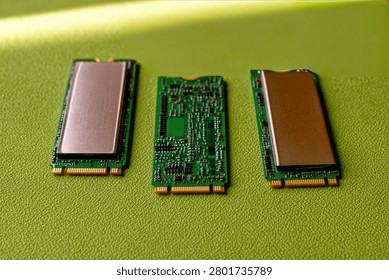 Three M.2 NVMe Solid State Drives are displayed on a vibrant green textured background. One SSD is shown with its cover removed, revealing the circuit board, while the other two are fully assembled.