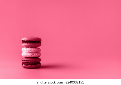 Three macaroons in stack toned in trendy magenta color of year 2023. Food concept. Copy space. Close-up.