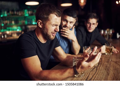 Three Male Friends In The Bar. Supporting Sad Friend. Unity Of People. With Beer On The Table.