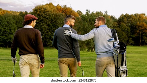 Three male friends with clubs and golf bag walking on the pitch. Back view - Powered by Shutterstock