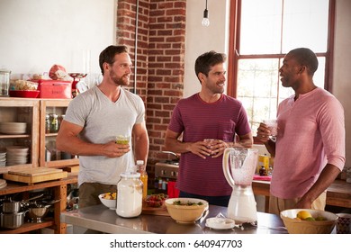 Three male friends drinking homemade smoothies in kitchen - Powered by Shutterstock