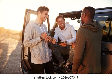 Three male friends on a road trip using a tablet computer