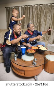 Three Male Generations Of An African-American Family Watching Football Game On Tv.