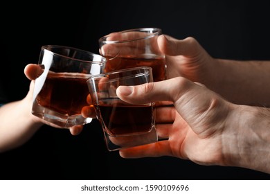 Three Male Hands Holds Glasses Of Whiskey On Black Background, Close Up. Cheers