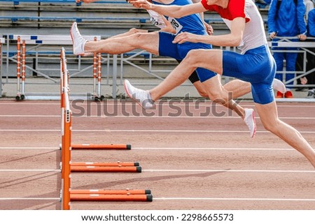 three male runners attack hurdle running 100 meters race in summer athletics championships
