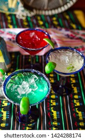 Three Margatia Drinks In Colors Of Mexican Flag On Mexican Table Cloth. Iced Drinks In Color