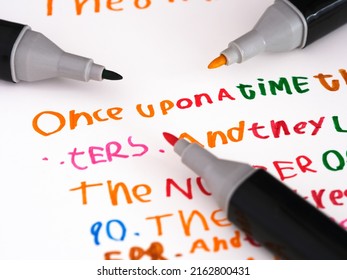 Three markers laying on a piece of paper with a story that is in a childs handwriting Once upon a time...