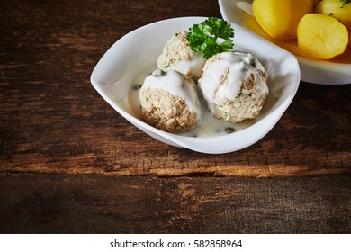 Three Meatballs Served With A Creamy White Sauce Beside Potatoes With Herbs. In German It Called Königsberger Klopse.