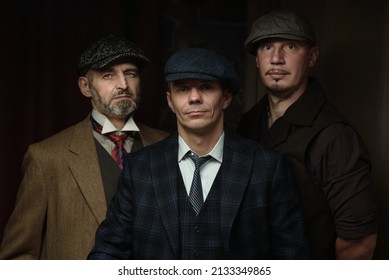 Three Men Of Different Ages, An English Retro Gangster Of The 1920s, Dressed In A Coat, Suit And Flat Cap