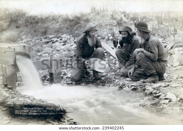 Three men,\
with dog, panning for gold in a stream in the Black Hills of South\
Dakota in 1889. Old timers, Spriggs, Lamb and Dillon may be die\
hard survivors from the Gold Rush of\
1876.