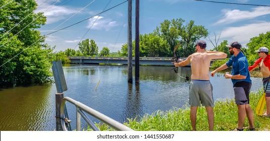 Three Men Fishing With Bow And Arrow In Missouri; Blue Sky In Background