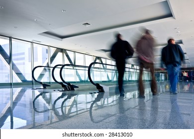 Drei Männer bewegen sich in grauem Korridor mit Rolltreppen im Bürozentrum