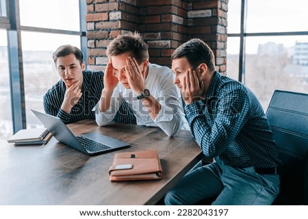 Three men in an office, fascinated and flabbergasted by what they're seeing on their laptop screens, The work seems to have left them stunned and astounded, unable to believe the information Stock foto © 