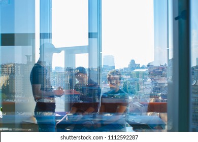 Three Men Are Seen Through The Glass. The Reflection Of The Big City In The Window Is Visible.