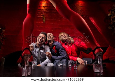 Three men sitting in front of dancing woman. They are looking confused and shocked. Front view