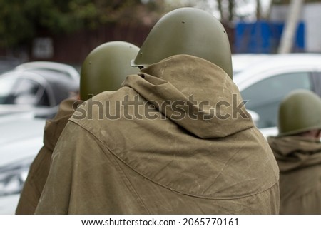Three men in Soviet uniform during the Second World War, view from the back. Green overcoat and helmet. Victory Day. City Lifestyle