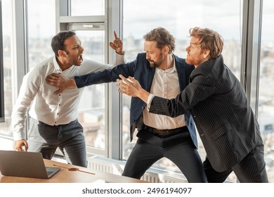 Three men in suits are engaged in a heated argument in a modern office setting. The man in the white shirt is yelling at the man in the blue suit, who is pushing him away - Powered by Shutterstock