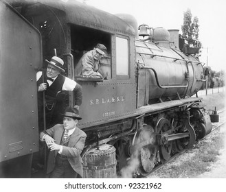 Three men waiting at  a steam locomotive