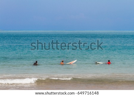 Three men waiting for a wave to surf at Barra beach in Salvador, Brazil