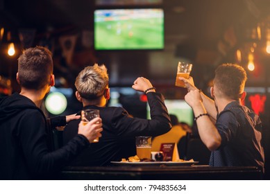 Three men watches football on TV in a sport bar