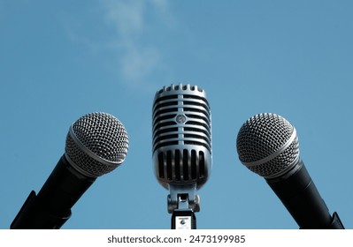 three microphones against the sky, microphones on blue background