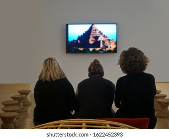 Three middle age women having a  funny conversation while watching film at tv. back, rear view.3 female wear black clothes. 