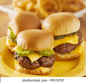 Three Mini Burger Sliders With Cheese And Pickeles.