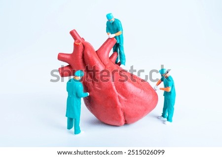 Three miniature surgeons interact with a large heart model, emphasizing surgical techniques and the study of human anatomy.