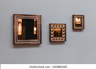 Three Mirror Frames On Grey Wall. Triptych Scenery Frames Mirrored Golden Copper Color.