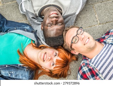 three mixed race friends lying on the ground, watching sky. concept about friendship,mixed race people, youth and people