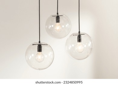 Three modern glass pendant lights suspended from the ceiling, each featuring a light bulb atop a frosted glass shade - Powered by Shutterstock