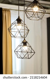 Three modern wire lampshades with glowing LED lamps in the interior. Modern wire ceiling lights. Art nouveau style home design. Selective focus