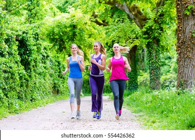 Three Motivated Women Jogging In Green Forest