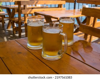 Three Mugs Of Beer On A Table In A Seaside Cafe