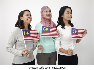 three multi racial malaysian holding flag looking away