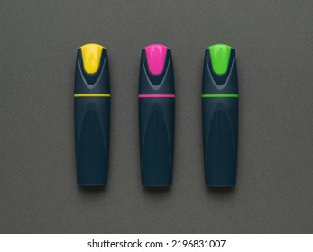Three multicolored capped markers on a gray background. The minimum concept of business and education. Flat lay.