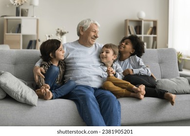 Three multiethnic adorable children boys enjoy conversation with loving hoary great-grandfather, multigenerational family spend weekend time together, having pleasant trustworthy talk in living room - Powered by Shutterstock