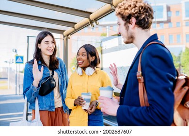 Three multiethnic happy friends meeting in bus stop at street of big city with an urban background. African and hispanic girl friends student with curly caucasian man commuting to university together. - Powered by Shutterstock