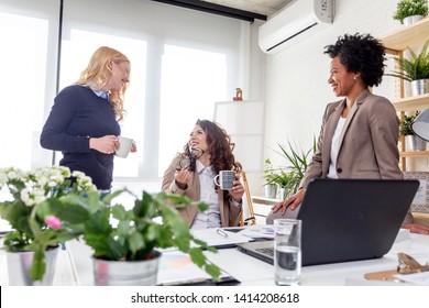 Three multiethnic woman drinking coffee and at the office discuss and smile - Shutterstock ID 1414208618