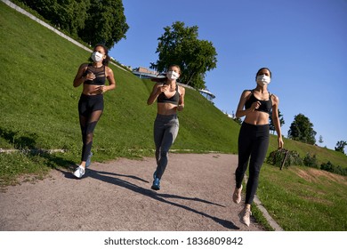 Three Multiethnic Women Runners Group Wear Face Masks Running Keep Social Distance Outdoor. Fit Healthy Diverse Ladies Wear Sportswear Jogging In Park On Nature Sport Track Distancing For Safety.