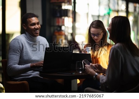 Three multiracial business colleagues having a meeting after work or during coffee break in a restaurant. Friends working at a cafe bar.
