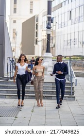 Three Multiracial Co Workers Are Smiling And Walking Together While Talking