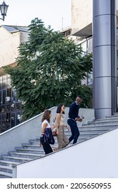 Three Multiracial Co Workers Are Walking Up The Stairs Together