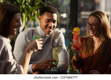 Three Multiracial Friends In A Bar Cheering. After Work Party With Cocktails After Successful Work Day.