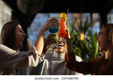 Three Multiracial Friends In A Bar Cheering. After Work Party With Cocktails After Successful Work Day.