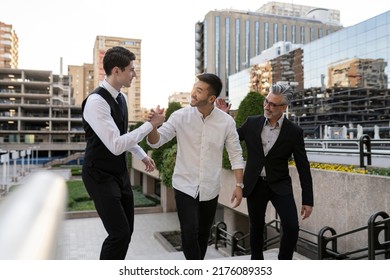 Three Multiracial Happy Colleagues Walking Outside Office Building, On The Way Out Waving Goodbye.