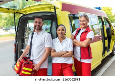 Three Multiracial Paramedics Standing In Front Of Ambulance Vehicle, Carrying Portable Equipment